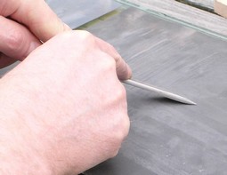 Honing a skew chisel on a piece of glass covered with sandpaper Honing a skew chisel on a piece of glass covered with sandpaper